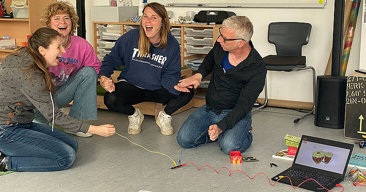 Referendar:innen bilden mit Händen einen Stromkreis