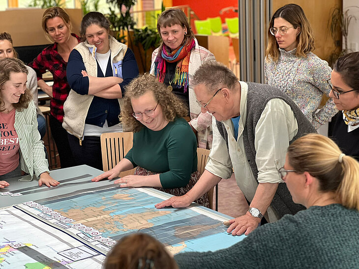 Kursteilnehmer:innen schauen eine Weltkarte an